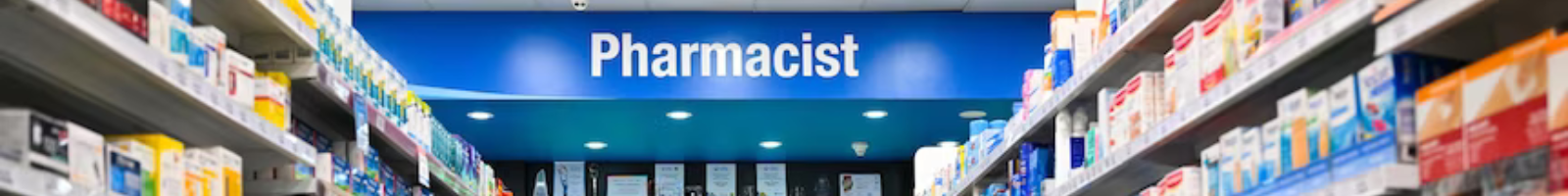 interior of pharmacy showing word Pharmacist and aislines of boxed medications and such