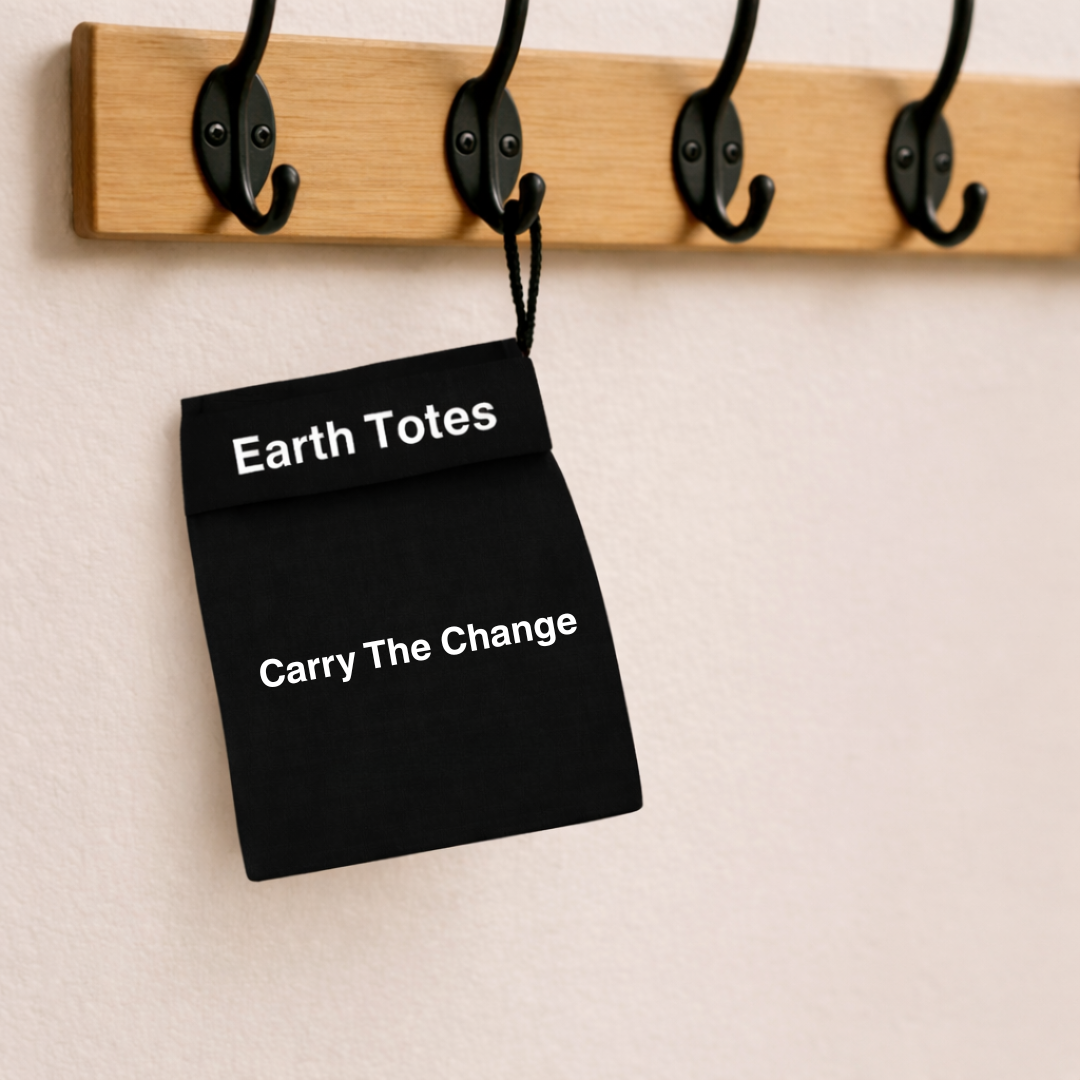 Black tote mesh bag with 'Earth Totes Carry The Change' text hanging on a wooden hook rack.